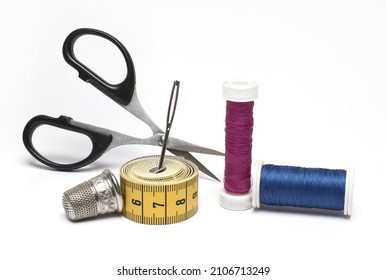 Close up of sewing kit scissors sewing needle different rolls of sewing thread and a thimble on white background as a concept for tailoring sewing and repairing clothes