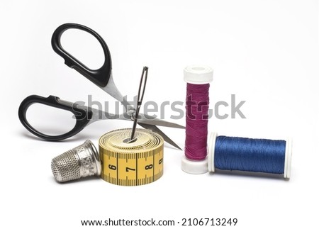 Close up of sewing kit scissors sewing needle different rolls of sewing thread and a thimble on white background as a concept for tailoring sewing and repairing clothes