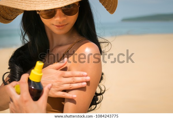 Close - up of Sexy asian woman are Spray\
Sunscreen , lotion or sunblock to body for prevent UV rays from\
sunlight Before the sun bathing in the summer or Vacation with sea\
and bluesky bckground