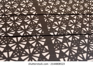 Close up shadow of the pattern formed by open weave rattan cane on a chair seat