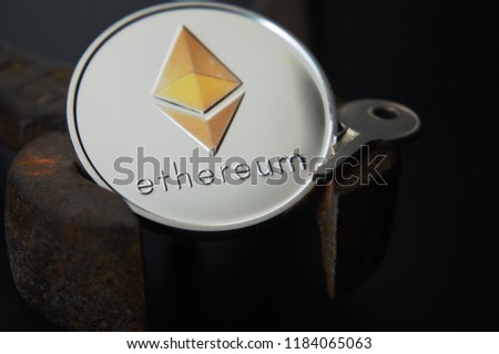 Close up of sheeny Ethereum coin and metal key on rusty vintage nippers. Cryptocurrency key code, secure Ethereum wallets concept. Black background selective focus with copy space