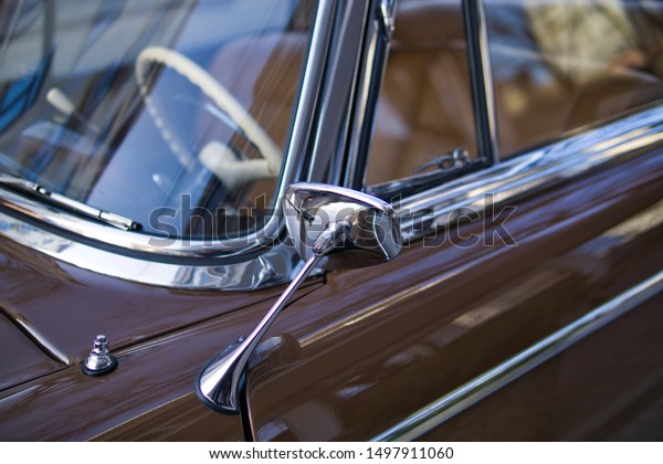 Close up of shiny chrome rear view\
mirror of classic car. Metal chrome side view mirror attached to\
the door of vintage car. Old car restoration\
concept.