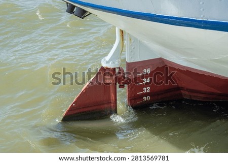 Close up of a ship rudder and draft marks on the hull in water