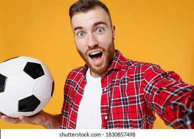 Close up of shocked man football fan in red shirt cheer up support favorite team with soccer ball doing selfie shot on mobile phone isolated on yellow background studio. People sport leisure concept - Shutterstock ID 1830857498
