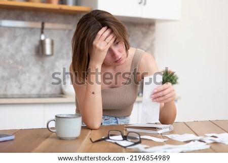Close up of shocked woman sitting at the table, stressed and confused by calculate expense from invoice or bills, have no money to pay mortgage or loan. High prices and spending money concept