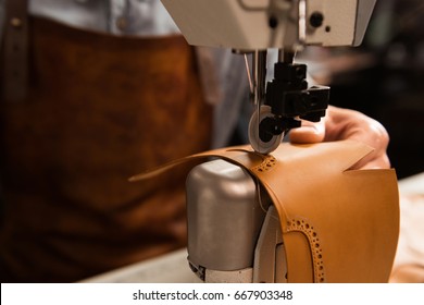 Close up of a shoemaker using sewing machine in workshop - Powered by Shutterstock