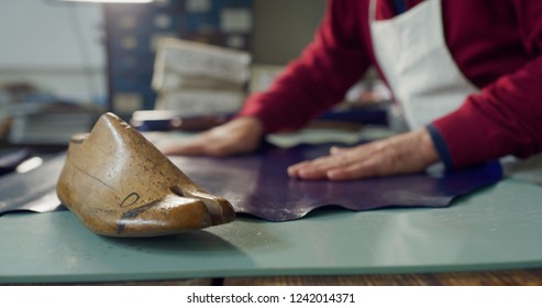 Close up of a shoemaker working a fabric in a shoe factory he is using the italian tradition. Concept: handmade, fashion, industrial, factory.