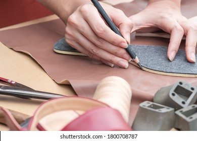 Close Up Shoemakers's Hands Drawing Or Drafting Woman Shoes Template For Cutting Leather With Tools And Accessories On Table.