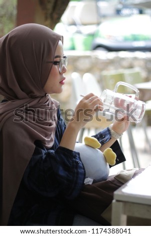 close up shoot of an Asian girl wearing hijab at open café in the park.