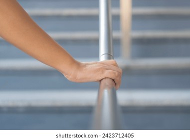 Close up shoot on a hand catching a stair rail. Woman aware about safety while walking on the stair way. Walking up or go down.