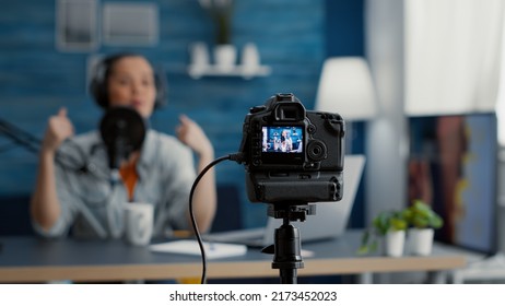 Close Up Shoot Of Professional Camera Recording Vlogger Talking To Audience. Famous Social Media Influencer Filming Vlog For Internet Video Sharing Platforms While Sitting At Home Studio Desk.