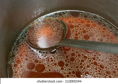 Close Up Shop Of A Pot Of Rich Meat Stock With A Ladle