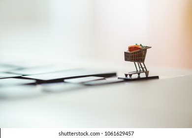 Close up of shopping cart or trolley miniature figure toy on laptop computer. Shopping, retail and e-commerce concept.