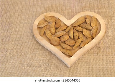 Close up shot of Almonds in the heart shaped wooden plate - on burlap background - Powered by Shutterstock