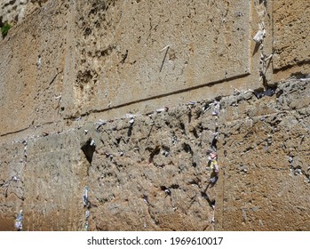 close up shot of the ancient limestone Wailing Wall or Western Wall in Jerusalem Israel with slips of paper containing prayer notes in the crevices
