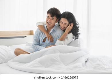Close Up Shot Of Asian Couple On Bed Together, They Smile And Hug Each Other With Love.