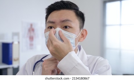 Close Up Shot Asian Medical Worker Is Wearing His Mask Properly Before Leaving His Office To Get Down To Work In The Hospital.