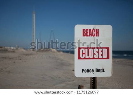 Close up shot of a beach closed sign on a NJ public beach with a amusment park in the background