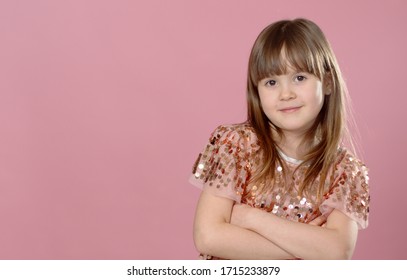 Close up shot of beautiful blonde Caucasian little girl wearing sequin dress, looking at the camera with adorable smile, posing against pink copy space background. Happy childhood concept