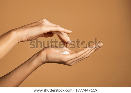 Close up shot of beautiful female hands holding and applying moisturiser. Beauty woman hand applying cream. Beautiful girl on creamy background holding moisturizer.