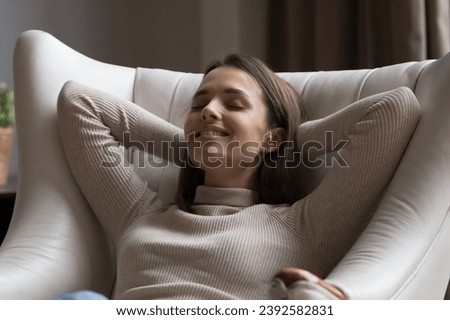 Close up shot beautiful smiling young woman relax leaned on cozy leather armchair, enjoy carefree weekend leisure and comfort furniture. Climate control, fresh conditioned air at modern home concept