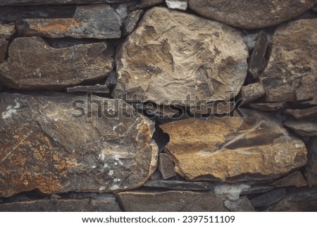Close up shot of a beautifully textured dry stone wall. Pattern Vintage Color Texture of Modern Style Design Decorative Uneven Cracked Real Stone Wall Surface with Cement for Construction Work.