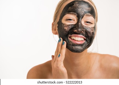 Close up shot of a beauty young woman using a black face mask - Powered by Shutterstock