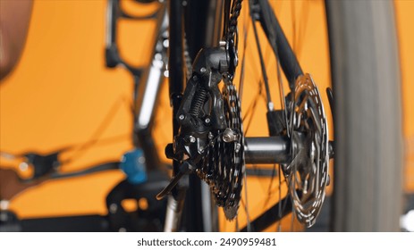 Close up shot of bicycle wheel mechanism being examined by woman during performance assessment. Focus on bike components tested by professional in blurry background ensuring proper function - Powered by Shutterstock