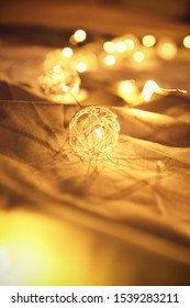 Close up shot of blurred golden Christmas lights on rumpled bed sheets, making cozy and romantic atmosphere. Festive bukeh background with lights.
