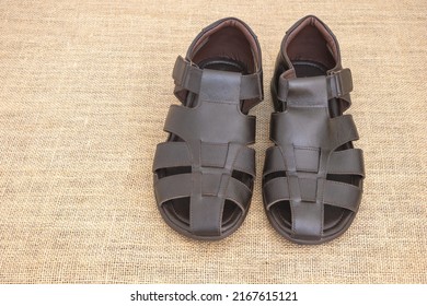 Close Up Shot Of Brown Sandals For Men And A Rustic Fabric Background.