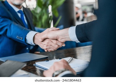 Close up shot of businessmen making handshake with partner, greeting, dealing, merger and acquisition. Hands of senior and young businessmen shaking after agreement on meeting