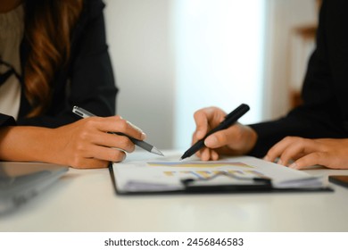 Close up shot of businesspeople analyzing stock market information on office table - Powered by Shutterstock