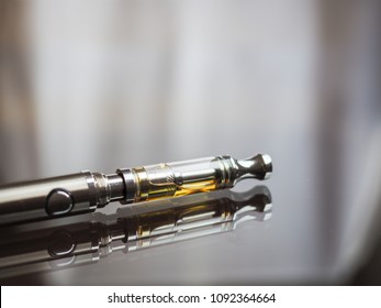 close up shot of cannabis oil in te cartridge on vape pen or call e-marijuana with reflection on dark surface with text space on the top