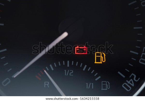 Close up shot of a\
car dashboard with the battery icon lit. Empty fuel gauge warning\
light in car dashboard