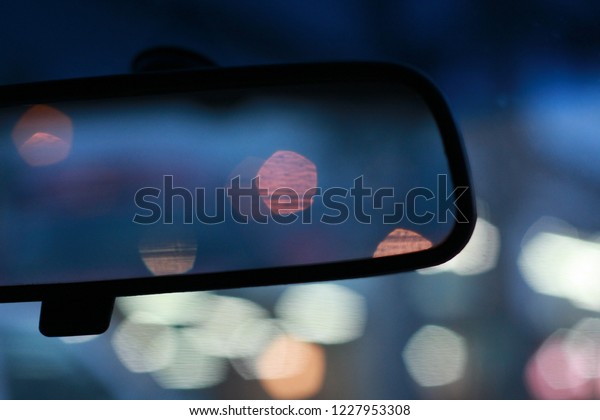 Close up shot of car rear view mirror at night with\
beautiful, glamorous and dreamy bokeh of city lights. Urban\
Lifestyle, Night life.