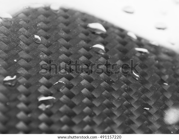 Close up shot of carbon fiber and water drop\
on the surface showing\
waterproof