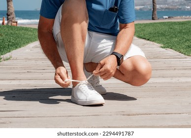 Close up Shot of Caucasian Elderly Man Tying his Shoe Laces. Mature Man in Outdoor at Sea in Sunny Day - Powered by Shutterstock