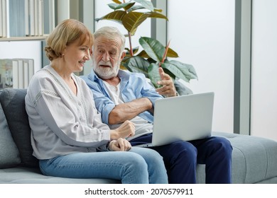 Close Up Shot Of Caucasian Old Senior Elderly Grandparents Lover Couple Sitting Together On Couch In Living Room Look At Laptop Computer Screen Learning Internet Social Network Online On Website.