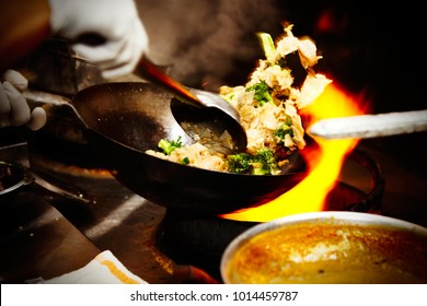 Close up shot of a chef in a kitchen cooking Thai fried rice with a wok