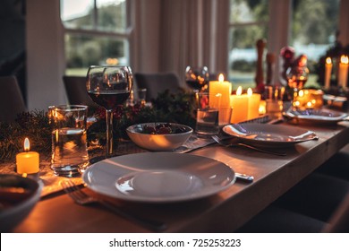 Close up shot of christmas festive table with no people. Dining table with plates, wine glasses and candles.