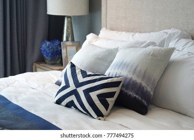 Close Up Shot Of Comfortable Blue Pattern Cushions And White Pillows On The White Bed