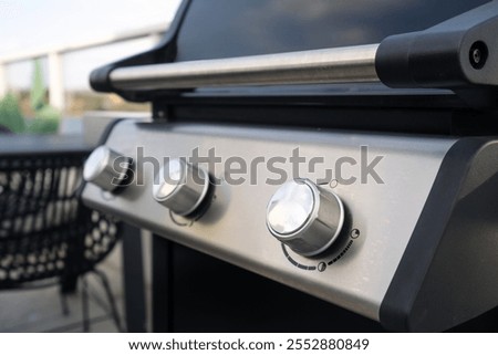 Close up shot of the control knobs on a gas grill with metallic handle. Modern barbeque equipment for roasting meat and vegetables on patio, selective focus