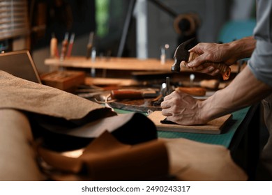 Close up shot craftsman using a hammer and other tools to shape and detail the leather piece - Powered by Shutterstock