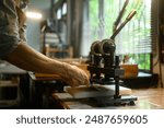 Close up shot craftsman working with manual leather die cutting machine in his workshop