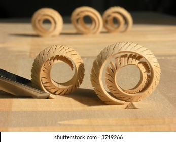 close up shot of curled woodshavings and chisel