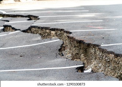 Close Up Shot Of Damaged Parking Lot Collapses With Huge Cracks By Natural Disaster. Asphalt Parking Floor Collapse And Falling Down From Bad Construction.