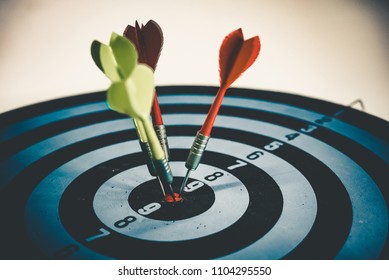 Close up shot of the dart arrow hit on bulleyes of dartboard to represent that the business reached the target of company with dark tone picture style. Target and goal as concept. - Shutterstock ID 1104295550
