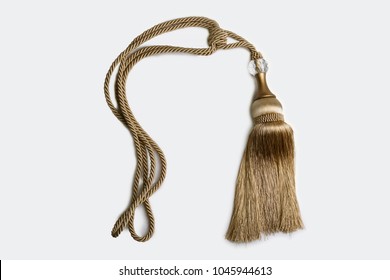 Close Up Shot Of A Decorative Tassel Knot With A Braided Rope In Gold Color Isolated In White Background