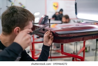 Close shot of dent removing without paint, young professional worker makes accurate blow rubber hammer  - Shutterstock ID 1959464272