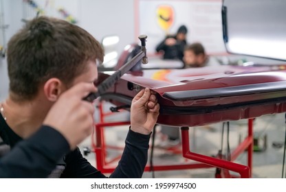 Close shot of dent removing without paint, young professional worker makes accurate blow rubber hammer  - Shutterstock ID 1959974500